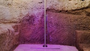 A stone-walled room with a metal pole and purple lighting. - Cozy and elegant B&B in the historic center of Belmonte. (Belmonte Calabro)