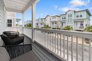 A covered porch with a view of multi-story houses, a street, and a clear sky. - Camp David 🌅 Soundside Escape in Gated Community | Pool + Hot Tub (Navarre)