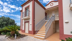 A two-story building with a staircase, a balcony, and a tiled entrance.