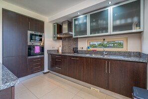 A modern kitchen with dark wood cabinets, stainless steel appliances, a granite countertop, and a window with a view. - Apartment 'Vale Da Pinta T1' with Shared Pool, Wi-Fi and Air Conditioning (Estômbar)
