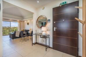 A hotel room with a balcony, a desk with a lamp, a large mirror, and a wooden door. - Apartment 'Vale Da Pinta T1' with Shared Pool, Wi-Fi and Air Conditioning (Estômbar)