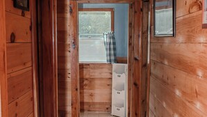 A wooden hallway with a window, a door, and a small white cabinet.