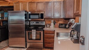 A modern kitchen with stainless steel appliances, wooden cabinets, and a built-in oven.