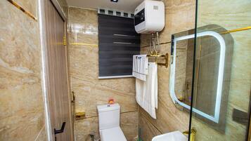 Een badkamer met toilet, wastafel, douchecabine van glas en een handdoekhouder.