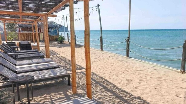 A beachside lounge with sun loungers and a bamboo pergola, overlooking the sea. - Apartment Ocean Side View Poseidon Building (Manta)