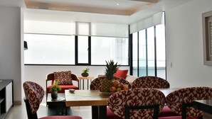 A dining area with a wooden table, patterned chairs, and a fruit bowl. - Apartment Ocean Side View Poseidon Building (Manta)