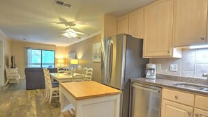A kitchen with a refrigerator, dishwasher, and a dining area with a table and chairs.