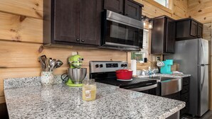 Una cocina con armarios de madera oscura, electrodomésticos de acero inoxidable, encimeras de granito y una olla roja en la estufa.