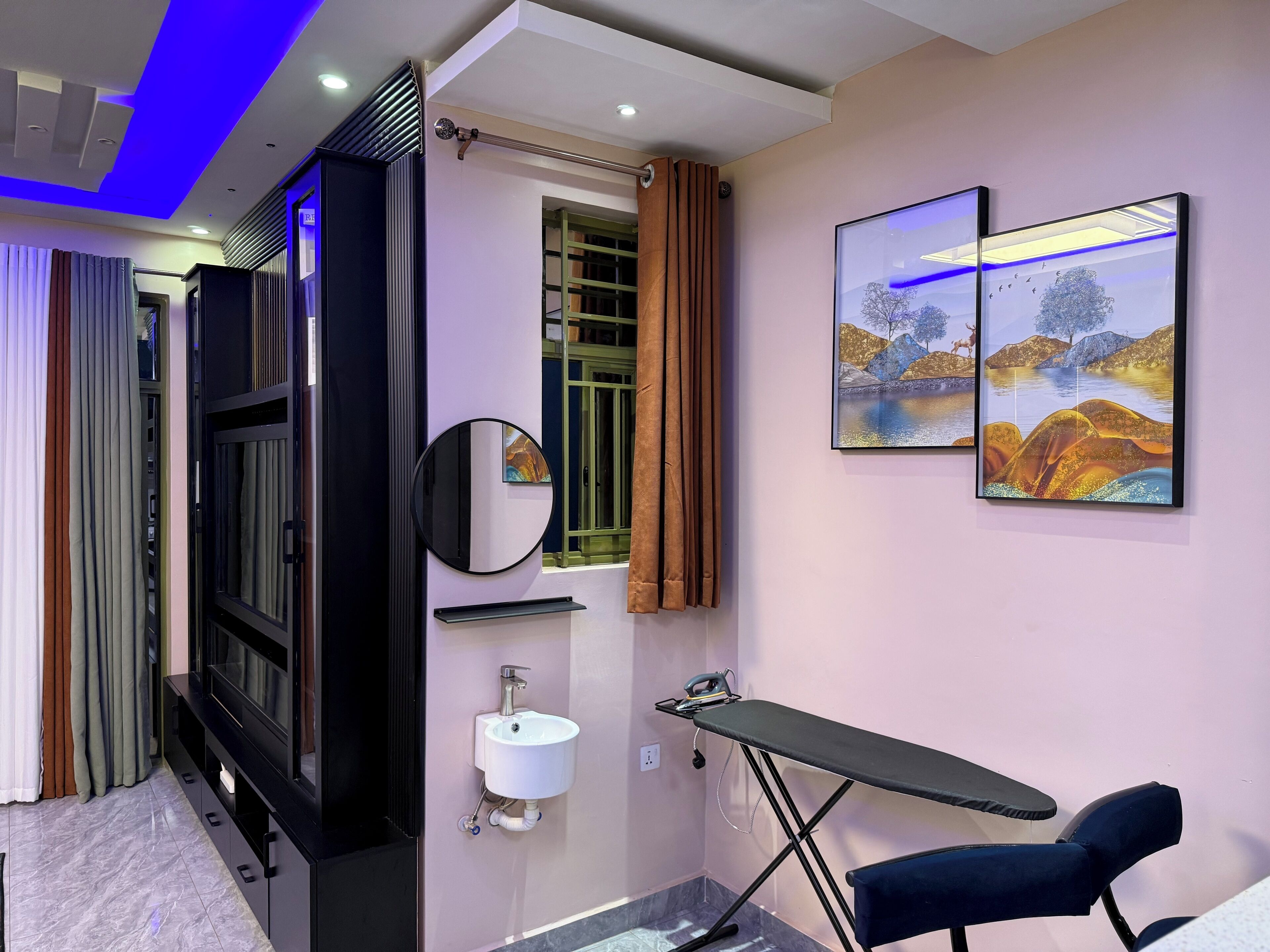 Een moderne badkamer met een wastafelmeubel, wastafel, spiegel en een wandplank waarop een strijkplank is bevestigd.
