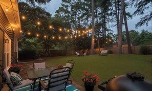 A backyard with a dining area, string lights, and a grill. - King Bed/ 2 Living-rooms/ Patio/ BBQ Grill (Norcross)