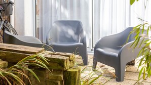 A patio area with two grey plastic chairs, a wooden table, and a bicycle.