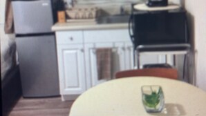 A kitchen with white cabinets, a refrigerator, a microwave, and a coffee maker.