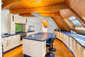 Una cucina con isola centrale, soffitto in legno e un lucernario.