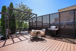 Una terraza de madera con una parrilla y dos sillas de mimbre.