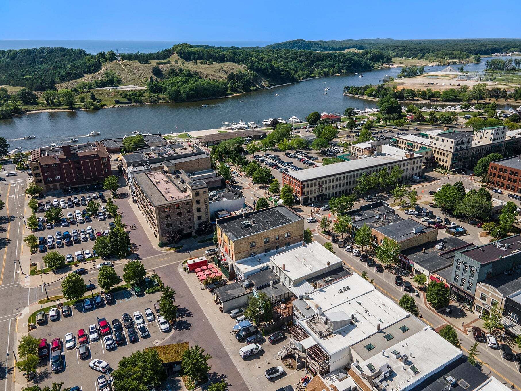 An aerial view of a town with a river, buildings, and a parking lot.