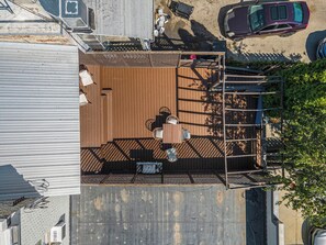 Vista aérea de una terraza con mesa y sillas, rodeada por una barandilla metálica y un cerco de madera.