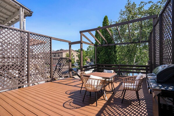 Una terraza al aire libre con una mesa y sillas de madera, una parrilla y vistas del entorno.
