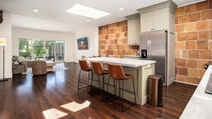 Una cocina moderna con una isla grande, taburetes de bar y un refrigerador de acero inoxidable.