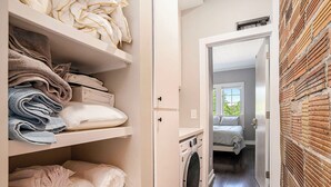 Un cuarto de lavandería con estantes llenos de toallas dobladas y una lavadora.