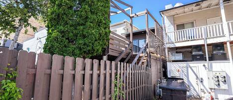 A residential building with a wooden fence, a staircase, and a dumpster.