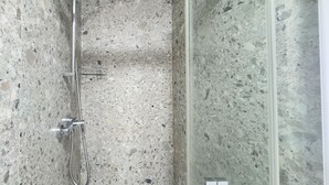 Een douche met een handdouche en een bedieningspaneel aan de muur.