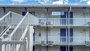 Een meerhoog hotel met balkons en airconditioners, met een bord waarop 'MALONEI' staat.