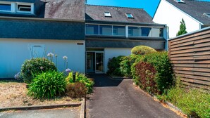 Ein zweistöckiges Haus mit überdachter Auffahrt, Garage und einem kleinen Garten mit verschiedenen Pflanzen.