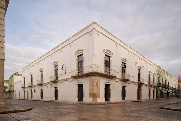 A large, white building with multiple balconies and arched windows.