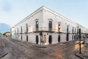 A white building with a balcony on the second floor, a street in front, and a clear sky.