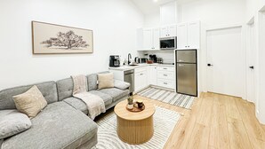 A modern kitchen with white cabinets, a stainless steel refrigerator, and a microwave.