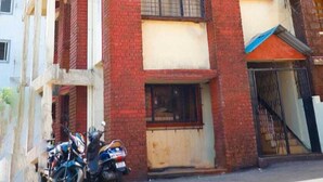 A multi-story building with a red brick facade, balconies, and a satellite dish. - Sai Residency  (Mahabaleshwar)