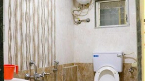 A bathroom with a toilet, shower, sink, and a water heater. - Sai Residency  (Mahabaleshwar)