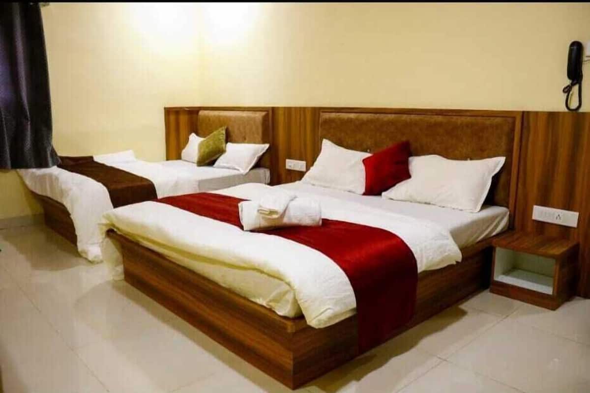 Un lit double avec une tête de lit en bois, deux tables de chevet et un coussin décoratif rouge.
