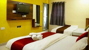 A hotel room with two beds, a television mounted on the wall, and a window with curtains. - Sai Residency  (Mahabaleshwar)