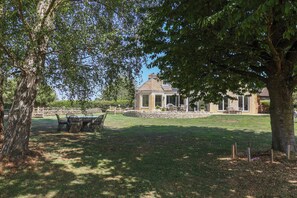 A gazebo with a stone base and glass panels, surrounded by a stone wall and a grassy lawn. - Leafield Cottage (Gloucester)