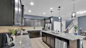 A modern kitchen with granite countertops, stainless steel appliances, and pendant lighting.