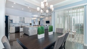 A modern kitchen with white cabinets, a dark wooden dining table, and a large island. - Storey Lake Resort/Modern Condo/Resort Facilities included/2 miles to Disney (Kissimmee)