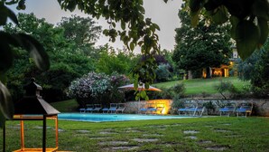 A well-maintained garden with a swimming pool, lounge chairs, and a stone pathway. - Dolce Collina 10, Emma Villas (Cesena)