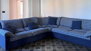 Ein Eckwohnzimmer mit einem karierten Sofa, einem gemusterten Boden und einer Ziegeldecke.