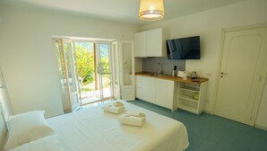 A bedroom with a bed, a TV, and a kitchenette. - Villa La Pigrizia - One Bedroom Villa, Sleeps 2 (Forio)