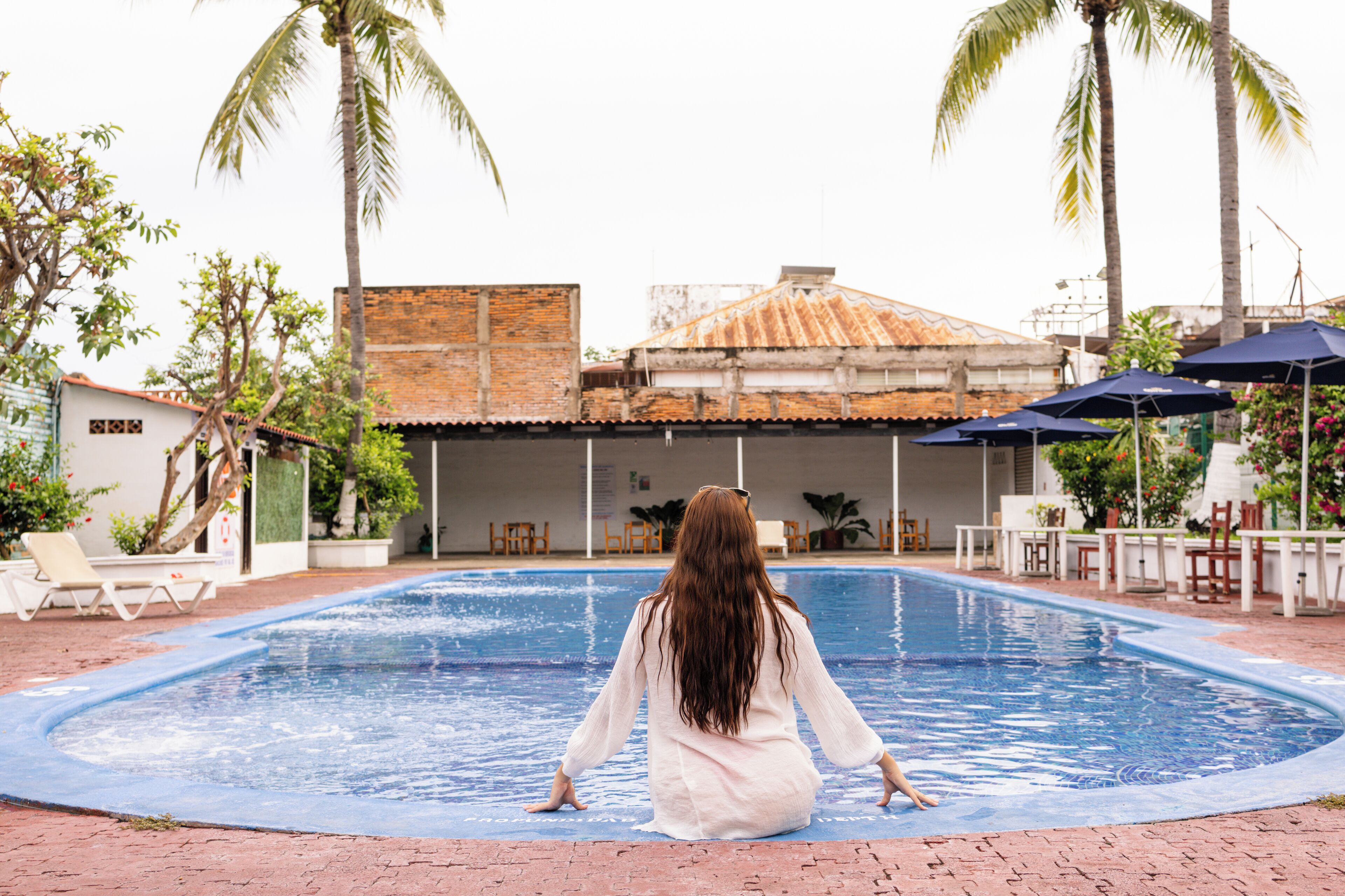 Una piscina al aire libre, sombrillas, sillones reclinables de piscina