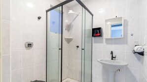 Un baño moderno con ducha de vidrio, lavamanos blanco y espejo.