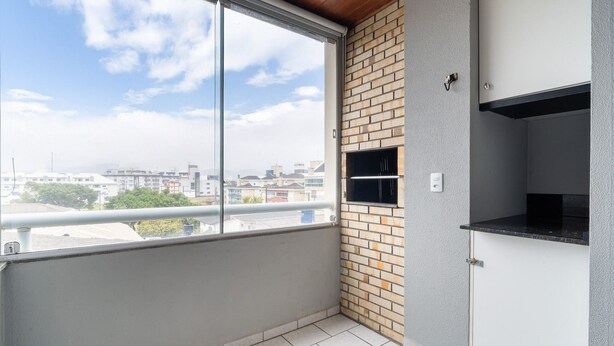 Un balcón con vista a la ciudad, un muro de ladrillo y una pequeña estantería.