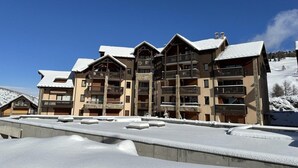 Ein mehrstöckiges Hotel mit Balkonen und einer Skipiste im Hintergrund.