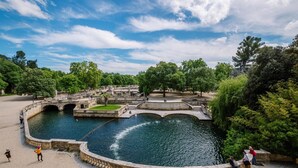 Un parc historique doté d’une fontaine centrale, de ponts en pierre et d’une végétation luxuriante.