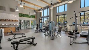 A gym with various exercise equipment, large windows, and a wooden ceiling. - Stylish & Clean Oasis | City Center | Pool & Gym (Tampa)