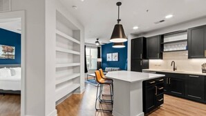 A modern kitchen with black cabinets, a large island, and a bar stool. - Stylish & Clean Oasis | City Center | Pool & Gym (Tampa)