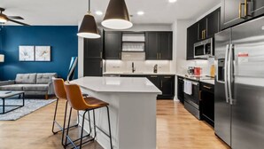 A modern kitchen with a central island, dark cabinetry, stainless steel appliances, and pendant lighting. - Stylish & Clean Oasis | City Center | Pool & Gym (Tampa)