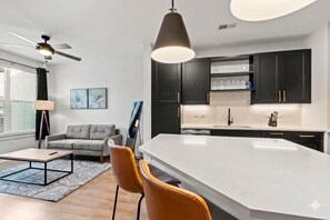Une cuisine moderne avec des meubles de couleur sombre, un grand îlot central et un ventilateur de plafond.