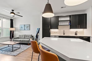 Una cocina moderna con armarios oscuros, una isla grande y un ventilador de techo.